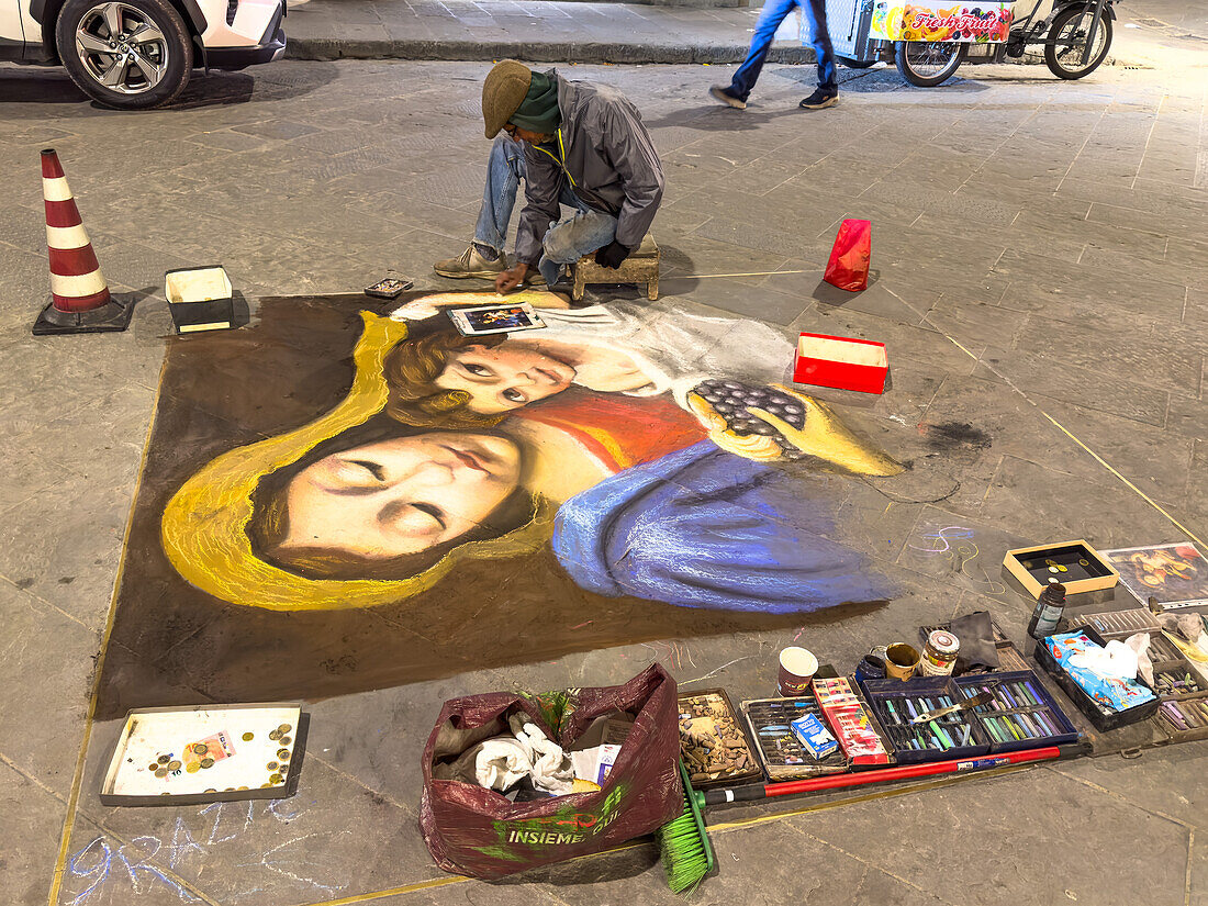 Ein Künstler reproduziert klassische Gemälde mit Kreide auf den Pflastersteinen einer Straße in Florenz, Italien, und arbeitet nur für Trinkgeld. Die Zeichnungen werden jede Nacht von der Straße gereinigt.