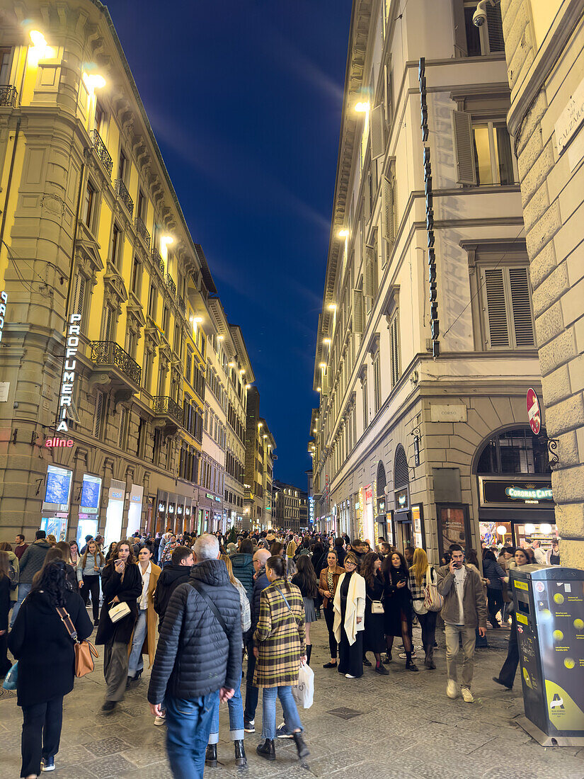 Pedestrians on the Via del Calzaiuoli at night in historic Florence, Italy.