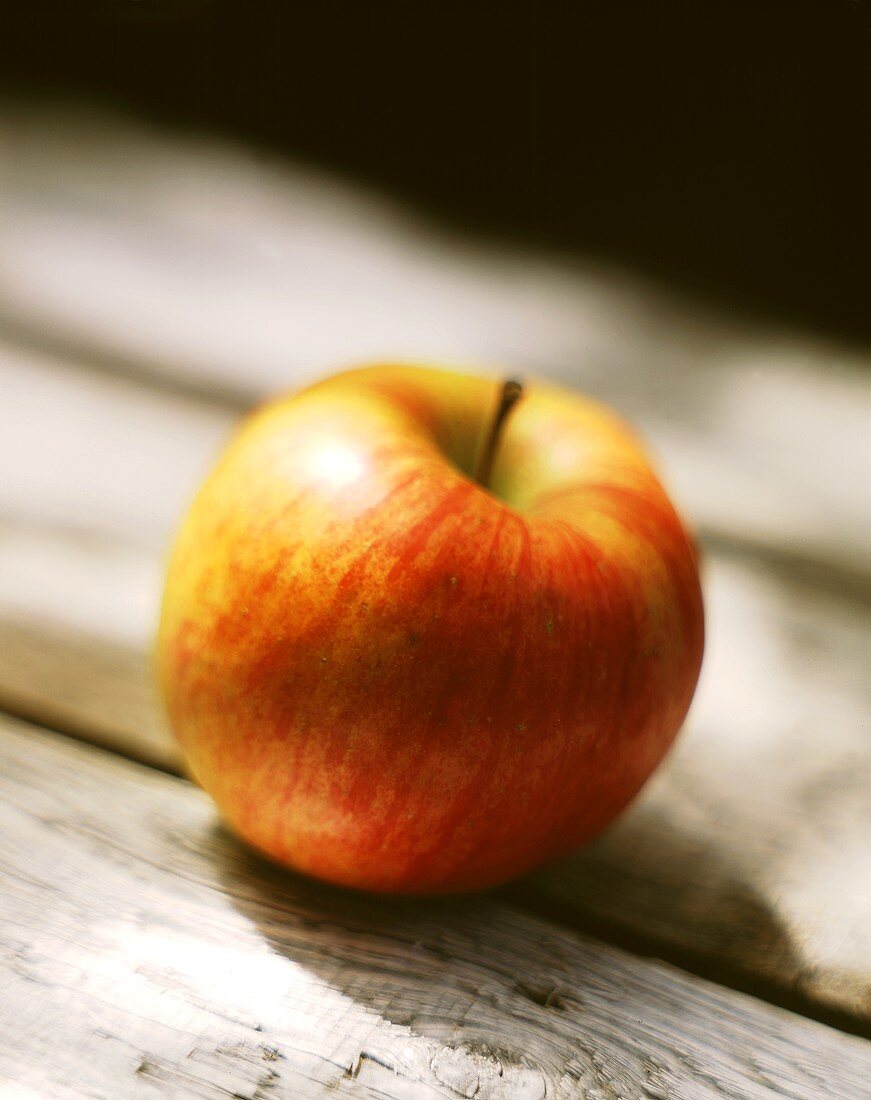 Ein Apfel der Sorte Jonagold auf Holzuntergrund