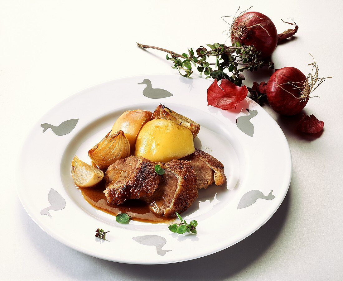 Gänsebrust mit roten Zwiebeln und Kartoffeln auf Teller