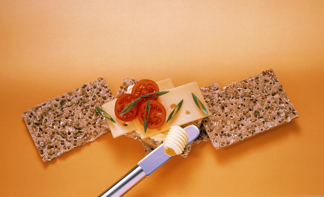 Knäckebrote, eins mit Käse- und Tomatenscheiben belegt