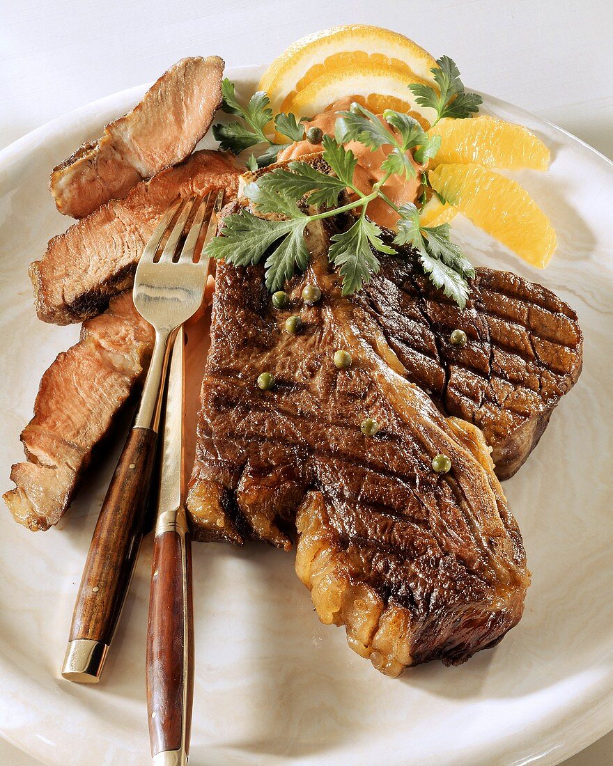 Gegrilltes T-Bone-Steak mit grünem Pfeffer und Orangenfilets