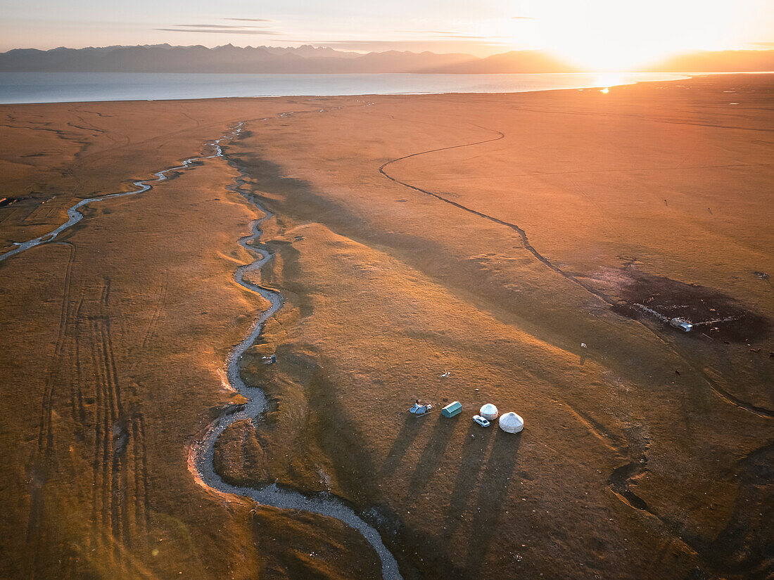 An aerial view of Son Kol lake area, with meandering river, yurts and camp at sunrise, Kyrgyzstan