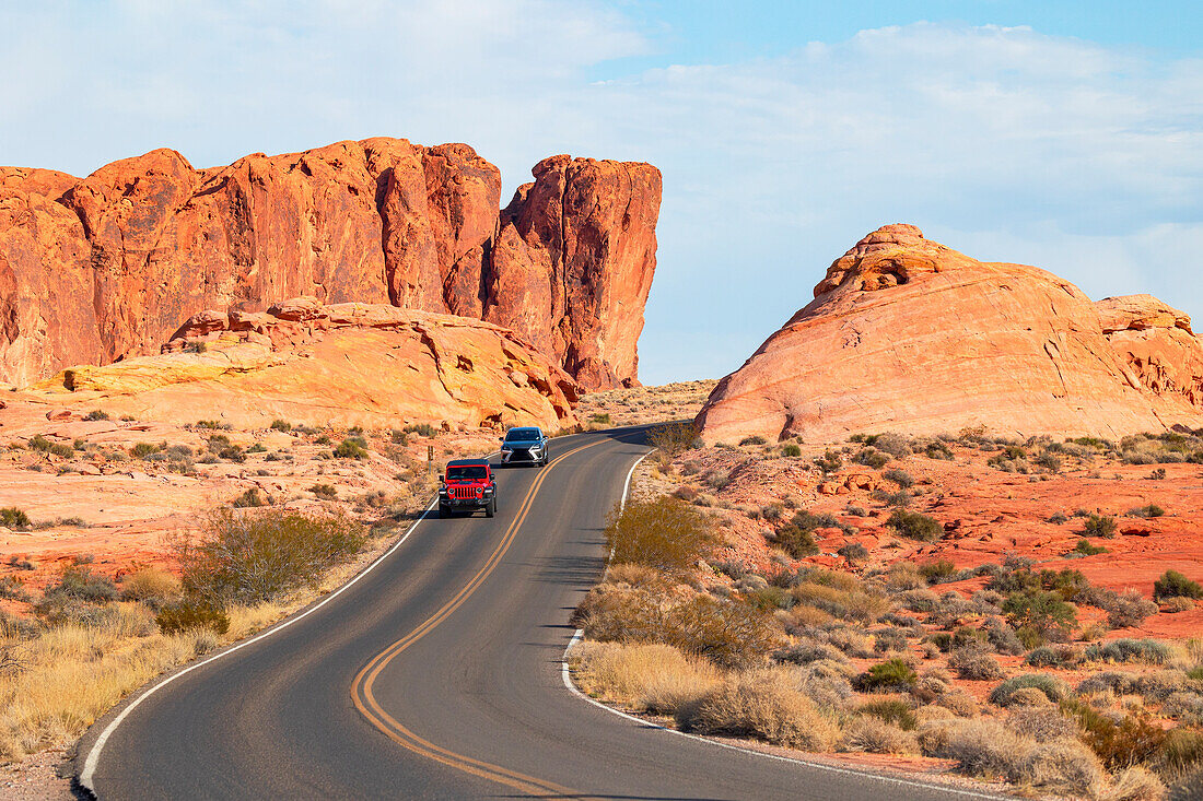 Zwei Autos fahren an einem sonnigen Sommertag die Panoramastraße im Valley of Fire State Park entlang, Nevada, Vereinigte Staaten von Amerika