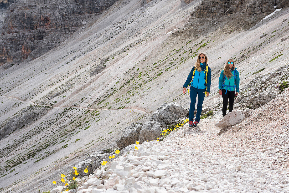 Zwei Wanderer beim Überqueren einer Geröllhalde, Naturpark Drei Zinnen, Dolomiten, Südtirol (Alto Adige), Italien