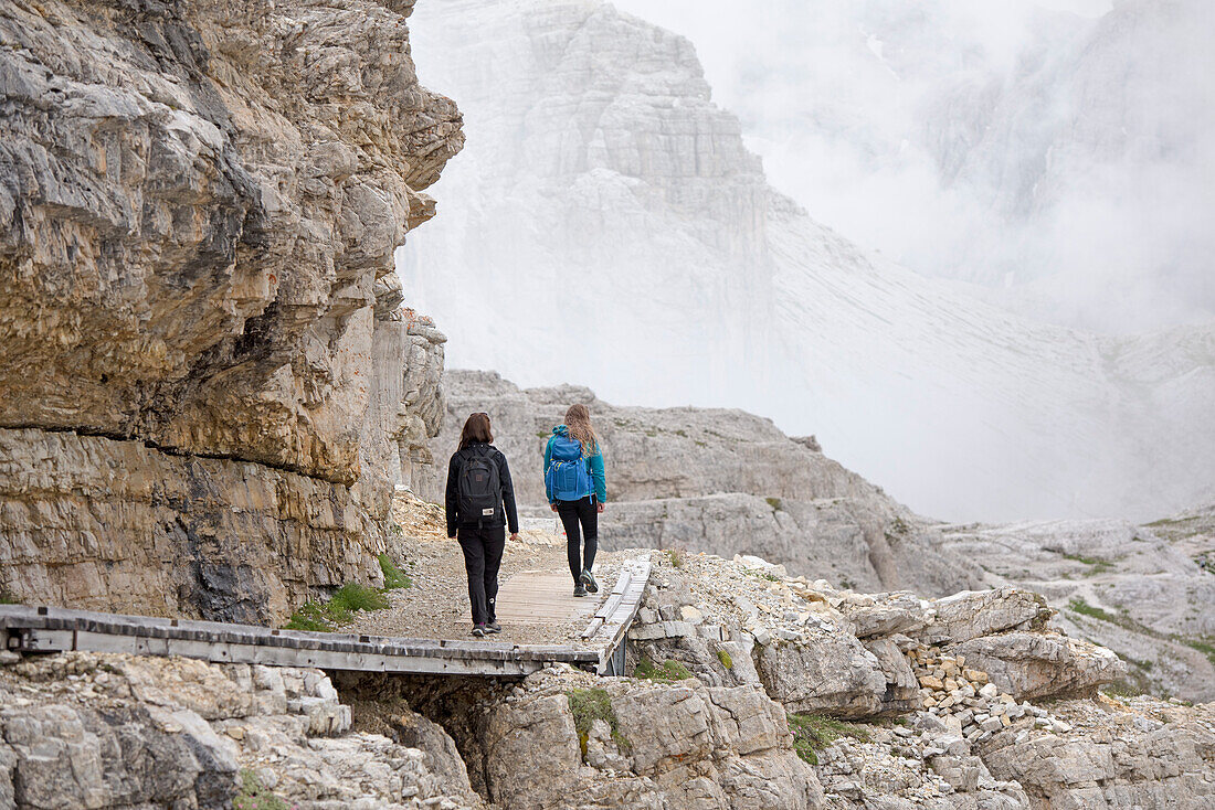 Wanderer auf dem Weg zwischen den Schutzhütten Locatelli und Pian di Cengia mit der Punta dei Tre Scarperi dahinter, Naturpark Drei Zinnen, Dolomiten, Südtirol, Italien