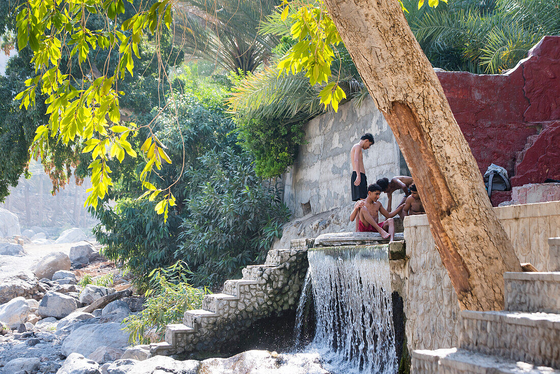 Junge Männer beim Baden in Al Thowarah (Nakhal Hot springs), Sultanat Oman, Arabische Halbinsel