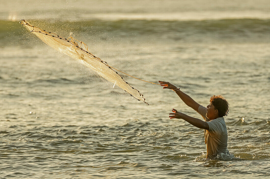 Mann wirft ein beschwertes Wurfnetz an der Boca Nosara (Flussmündung) aus, lokaler Angelplatz, Boca Nosara, Nosara Beach, Guanacaste, Costa Rica