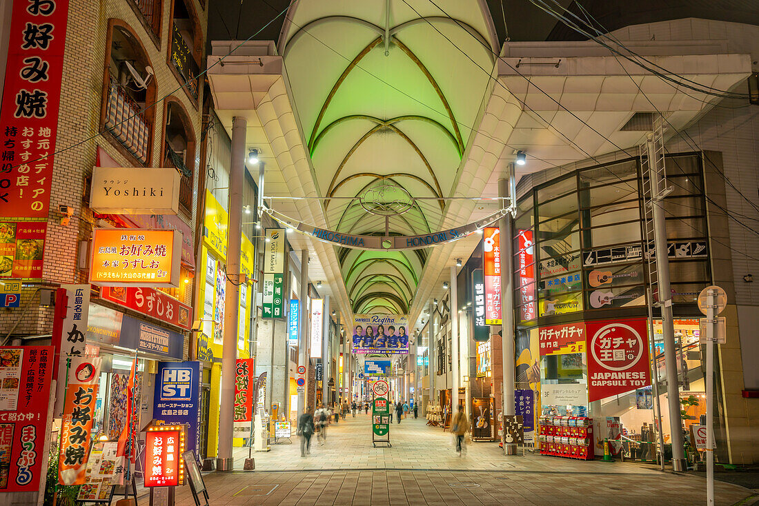 View of colourful shops and restaurants in shopping arcade at night, Hiroshima, Honshu, Japan