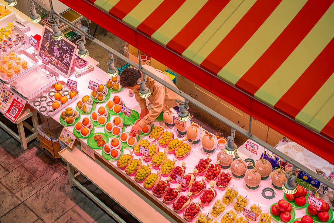 Elevated view of colourful fresh fruit stall and people in Omicho Market, Kanazawa City, Ishikawa Prefecture, Honshu, Japan