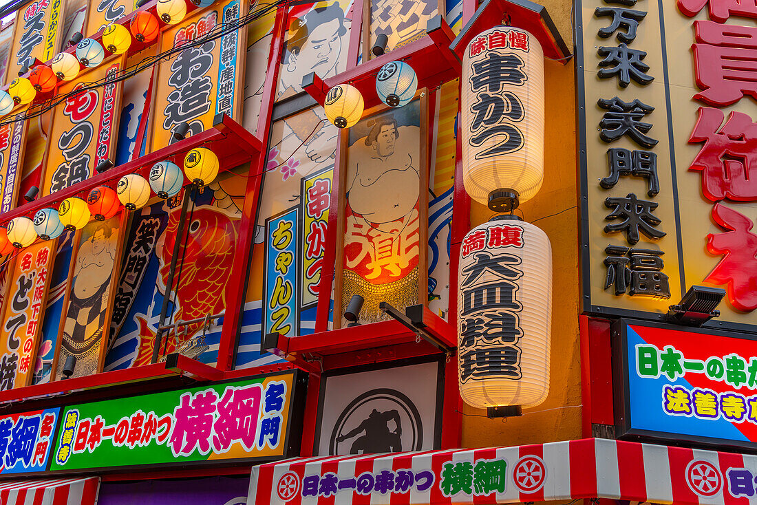 View of colourful facades of shops and restaurants in Dotonbori, vibrant entertainment district near the river, Osaka, Honshu, Japan