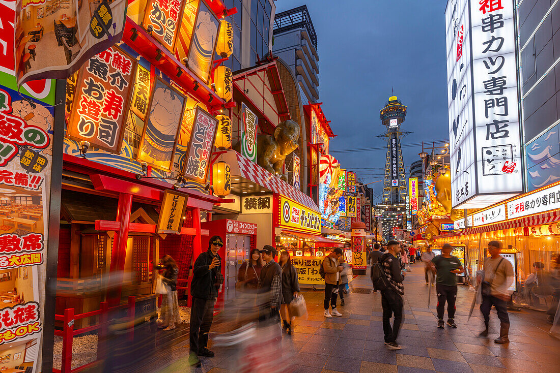 View of Tsutenkaku Tower and restaurants neon lights at dusk in the Shinsekai area, Osaka, Honshu, Japan