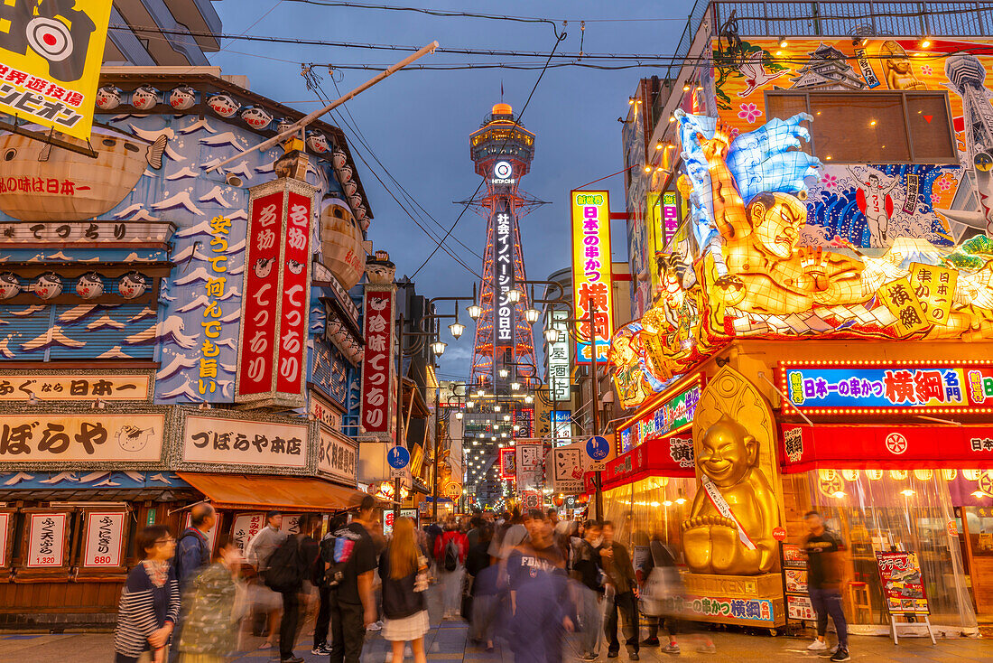 View of Tsutenkaku Tower and restaurants neon lights at dusk in the Shinsekai area, Osaka, Honshu, Japan