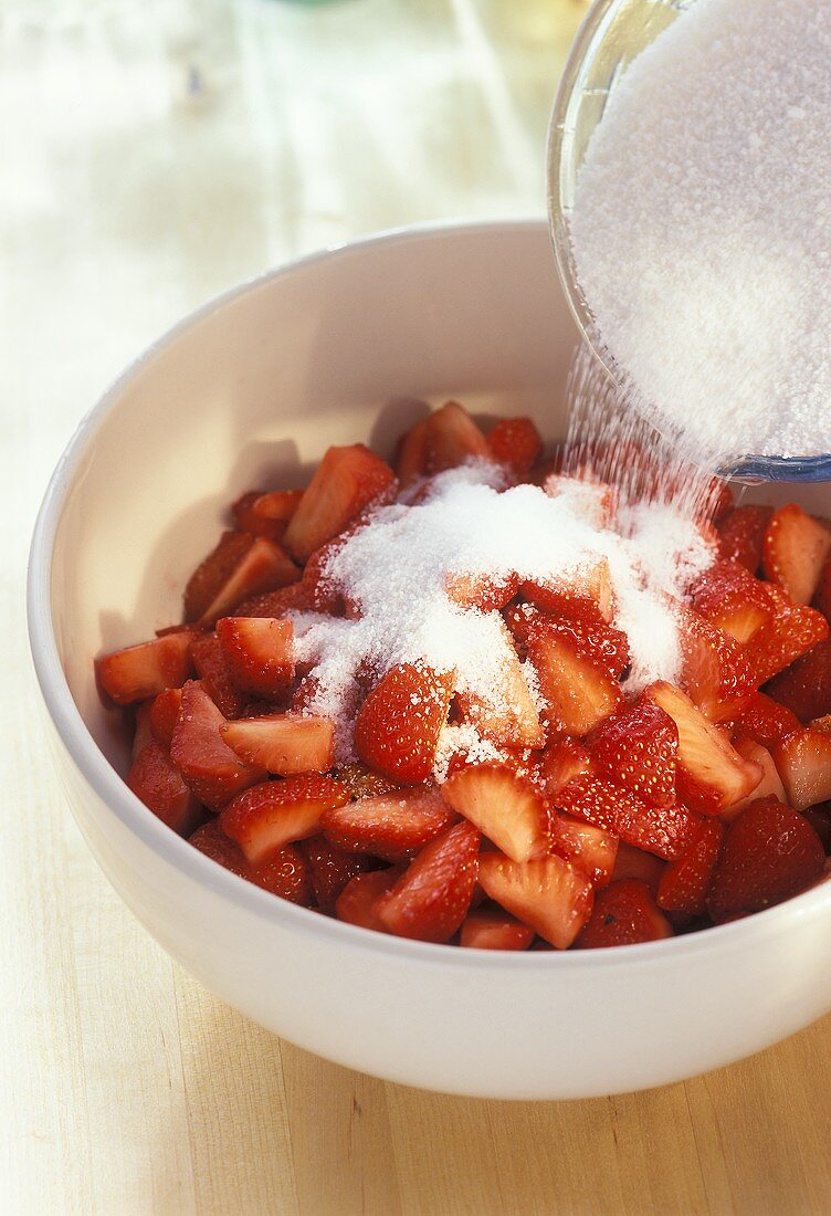Pouring Sugar Over a Bowl of Strawberries