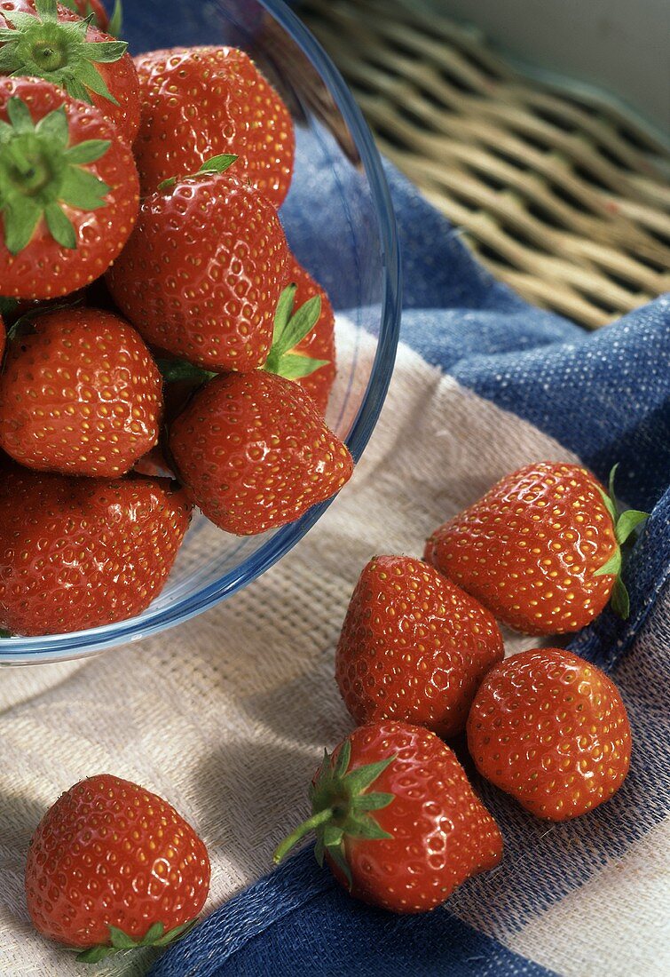 Erdbeeren im Glasschälchen und davor auf Küchentuch
