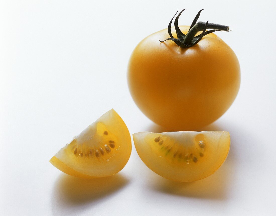 Eine Tomate und zwei gelbe Tomatenschnitze
