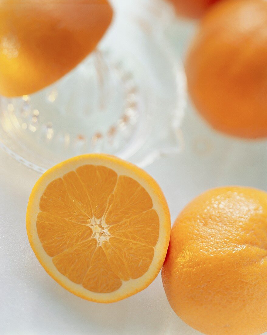Orangen, ganz und halbiert, mit einer Zitruspresse