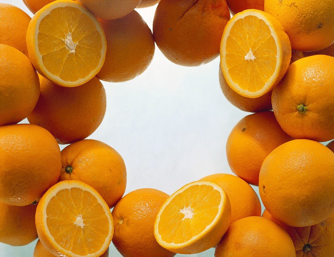 Lots of oranges, whole & halved, grouped round edge of picture