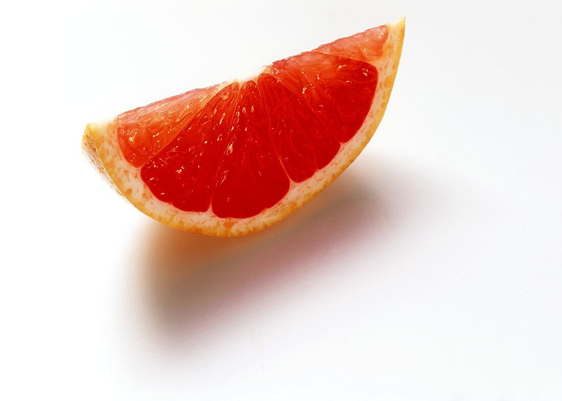 A wedge of pink grapefruit on white background