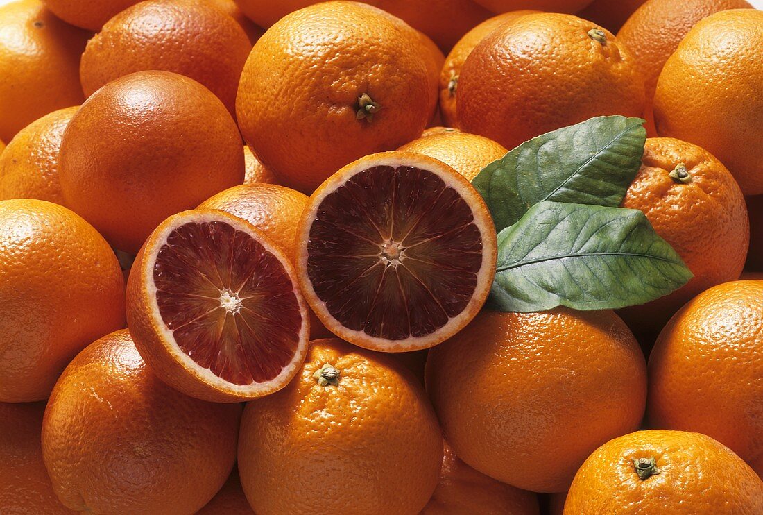 Blood oranges with two blood orange halves and leaves