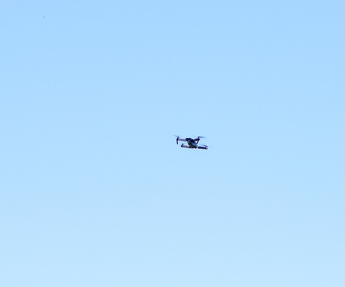 Kleine Drohne in der Luft vor blauem Himmel aus geringer Höhe