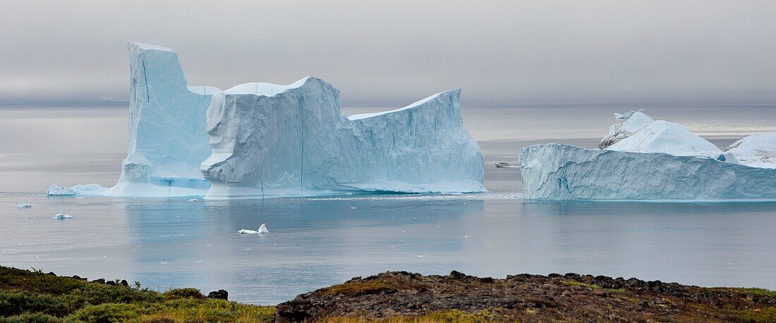 Greenland, west coast, Disko Island, Qeqertarsuaq, boat between two icebergs along the coast