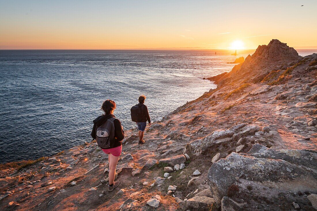 Frankreich, Finistere, Plogoff, Wanderer bei Sonnenuntergang an der Pointe du Raz