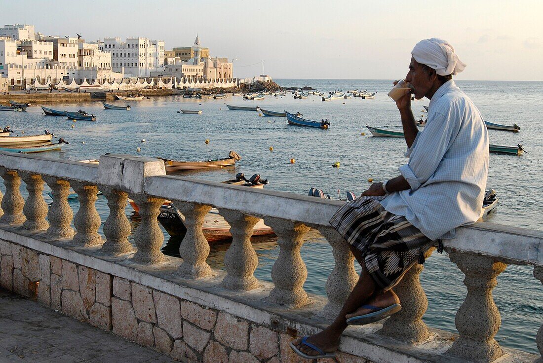 Yemen, Hadramaut Governorate, Al Mukalla, man drinking tea with milk and cardamon, sunset