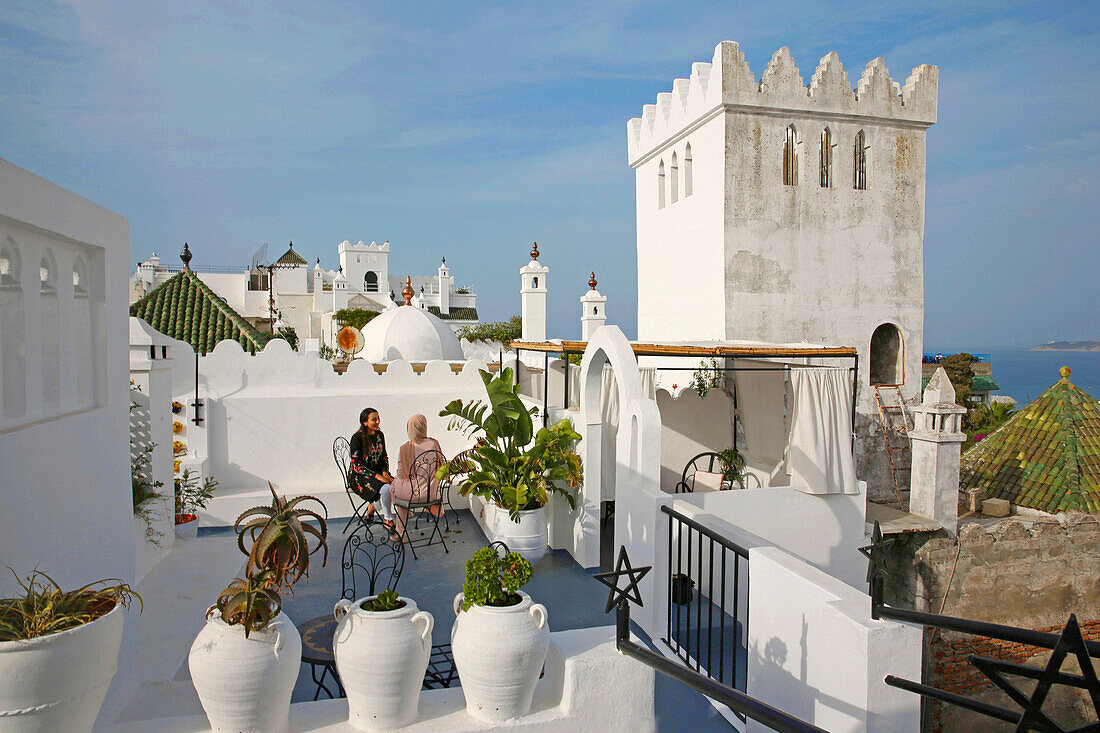 Morocco, Tangier Tetouan region, Tangier, Moroccan women on the terrace of the Abyssinian hotel in Tangier, facing a white crenellated tower overlooking the Mediterranean