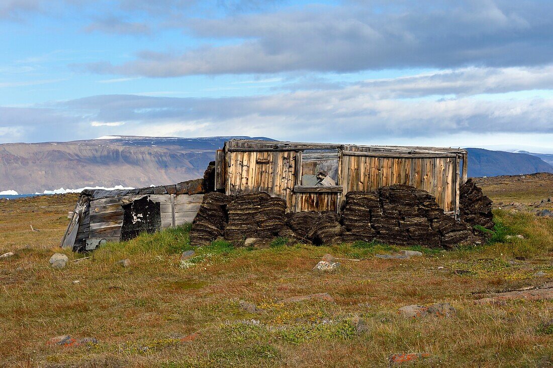 Greenland, West Coast, North Star Bay, Wolstenholme fjord, Dundas (Thule), Inuit Igloo, traditional house with peat walls and, from the beginning of the 20th century, an internal wooden structure, the ice cap in the background