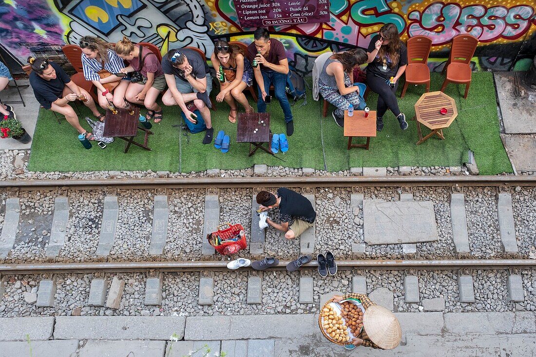 Vietnam, Hanoi, railroad that passes in the heart of the old town, tourists waiting for the passage of a train, shoe polisher