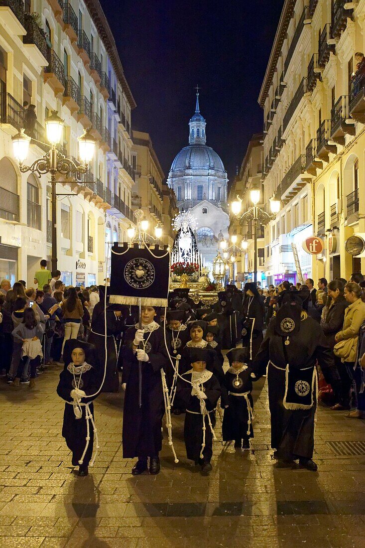 Spain, Aragon Region, Zaragoza Province, Zaragoza, Religious float being carried through the streets during Semana Santa, (Holy Week) celebrations, Basilica de Nuestra Senora de Pilar in the background