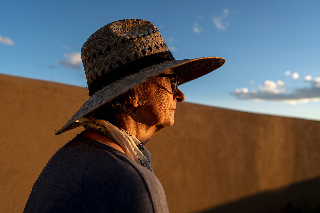 USA, New Mexico, Santa Fe, Frau mit Strohhut an einer Lehmziegelwand in der Hochwüste