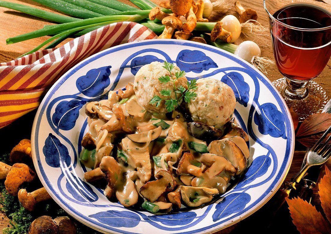 Forest mushrooms in cream sauce with bread dumplings on plate