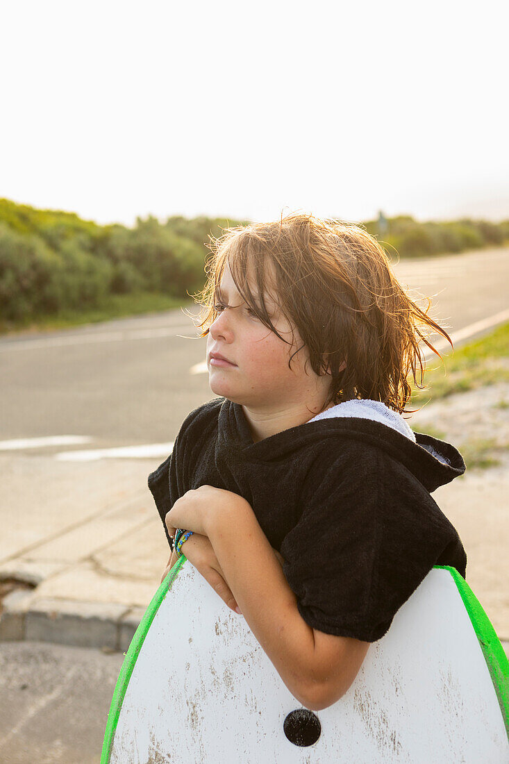 Südafrika, Hermanus, Porträt eines Jungen mit Surfbrett und Schwester am Strand