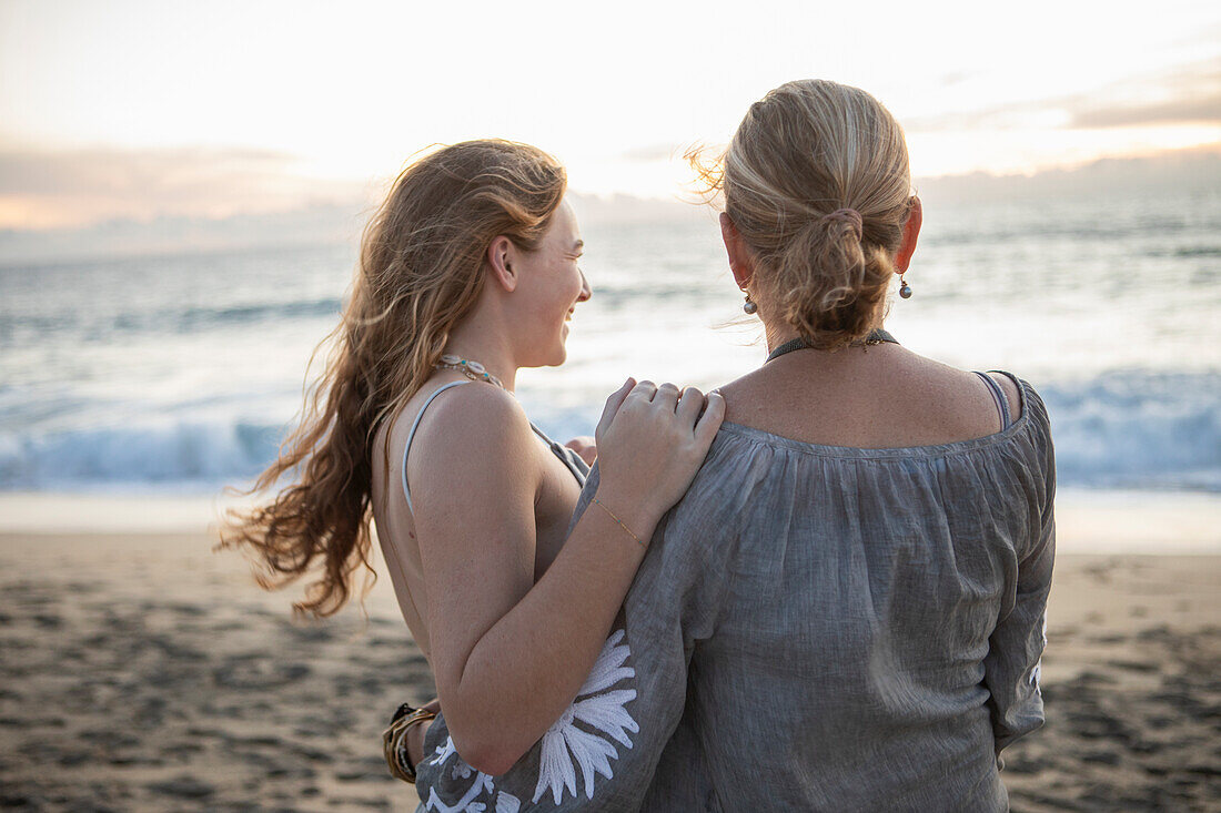 Rückansicht von Mutter und jugendlicher Tochter am Strand