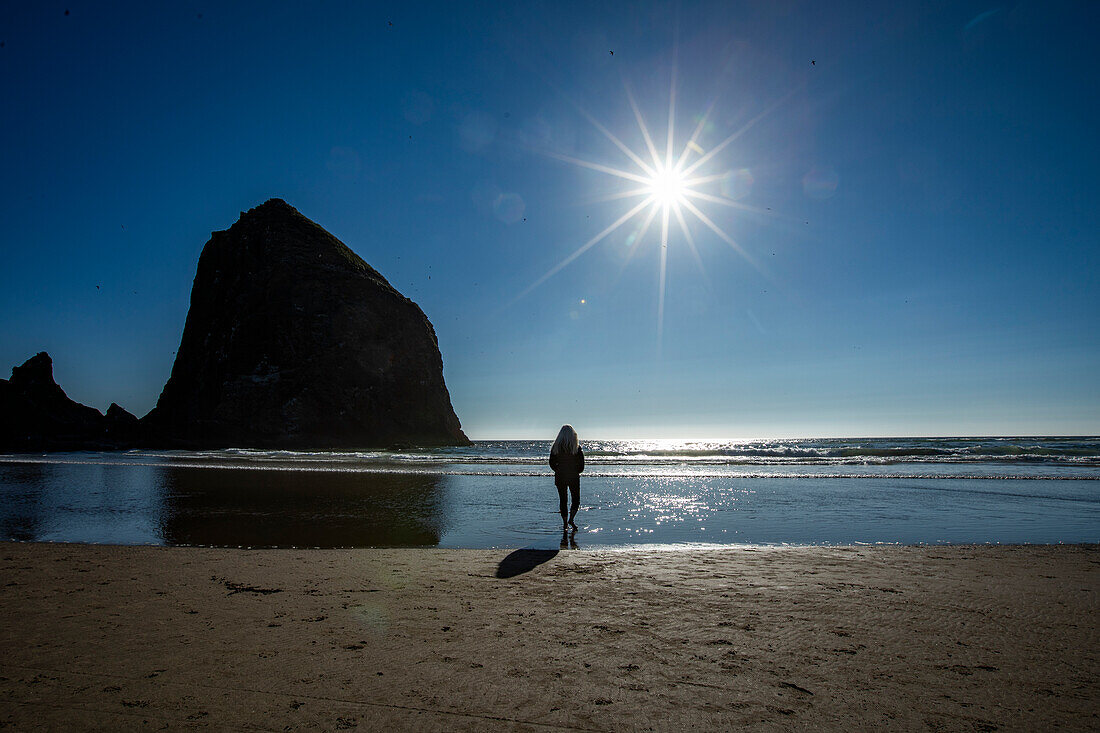 USA, Oregon, Silhouette einer Frau, die in der Nähe des Haystack Rock in Cannon Beach steht