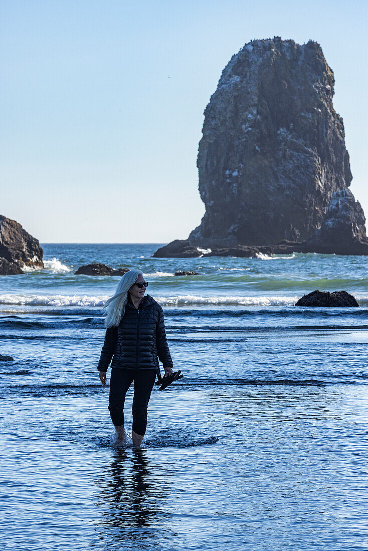 USA, Oregon, Woman wading in ocean at Cannon Beach 