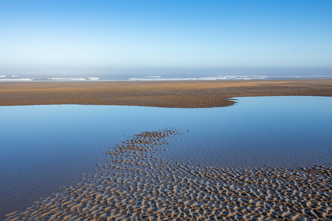 USA, Oregon, Flache Wassertümpel am sandigen Cannon Beach