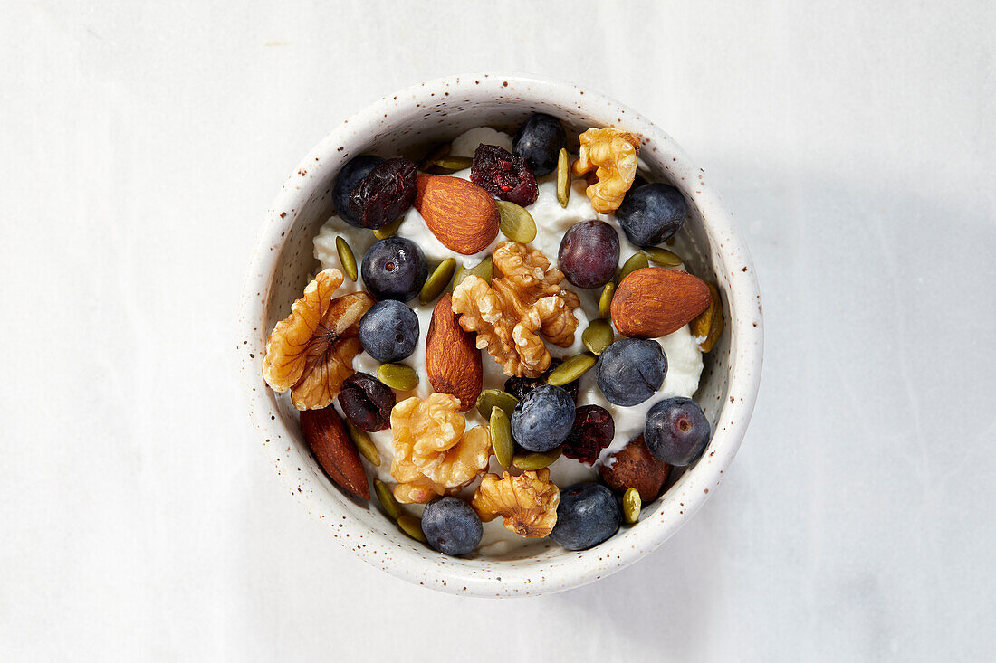 Draufsicht auf eine Schale mit Joghurt, Beeren und Nüssen