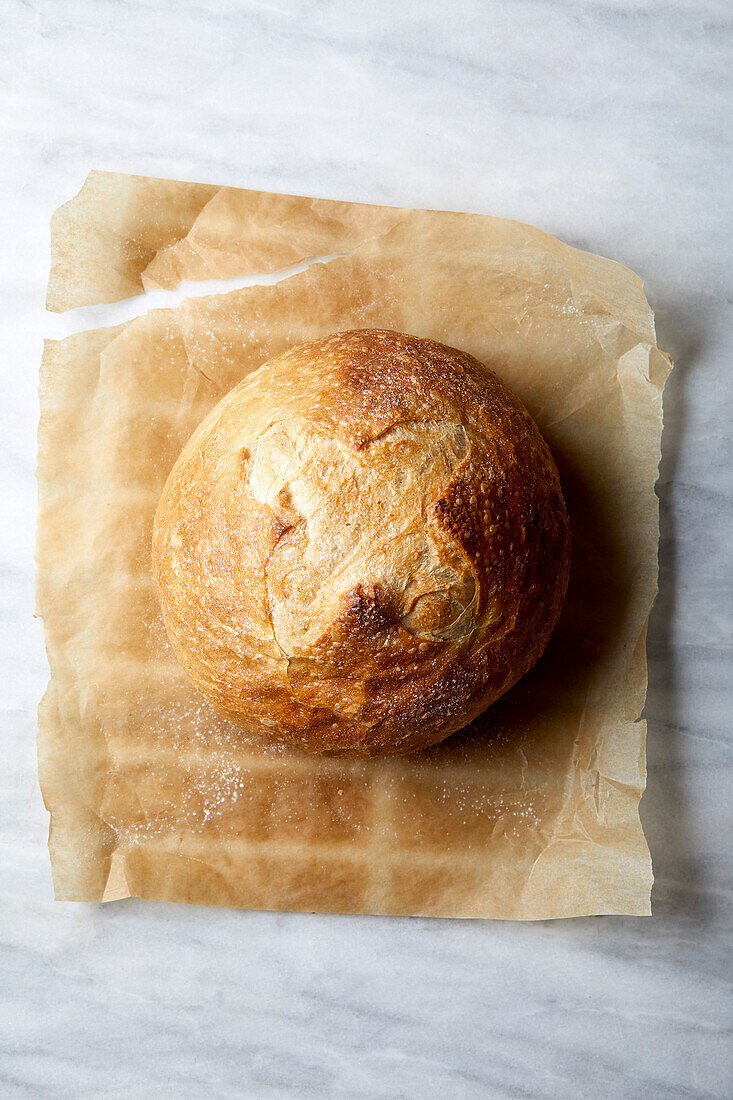 Draufsicht auf ein Sauerteigbrot auf Pergamentpapier