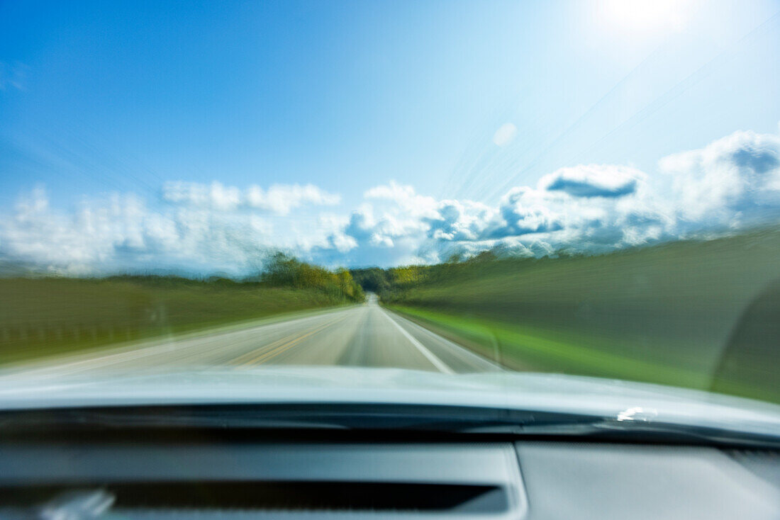 USA, Wisconsin, Landstraße und Wolken aus dem fahrenden Auto gesehen