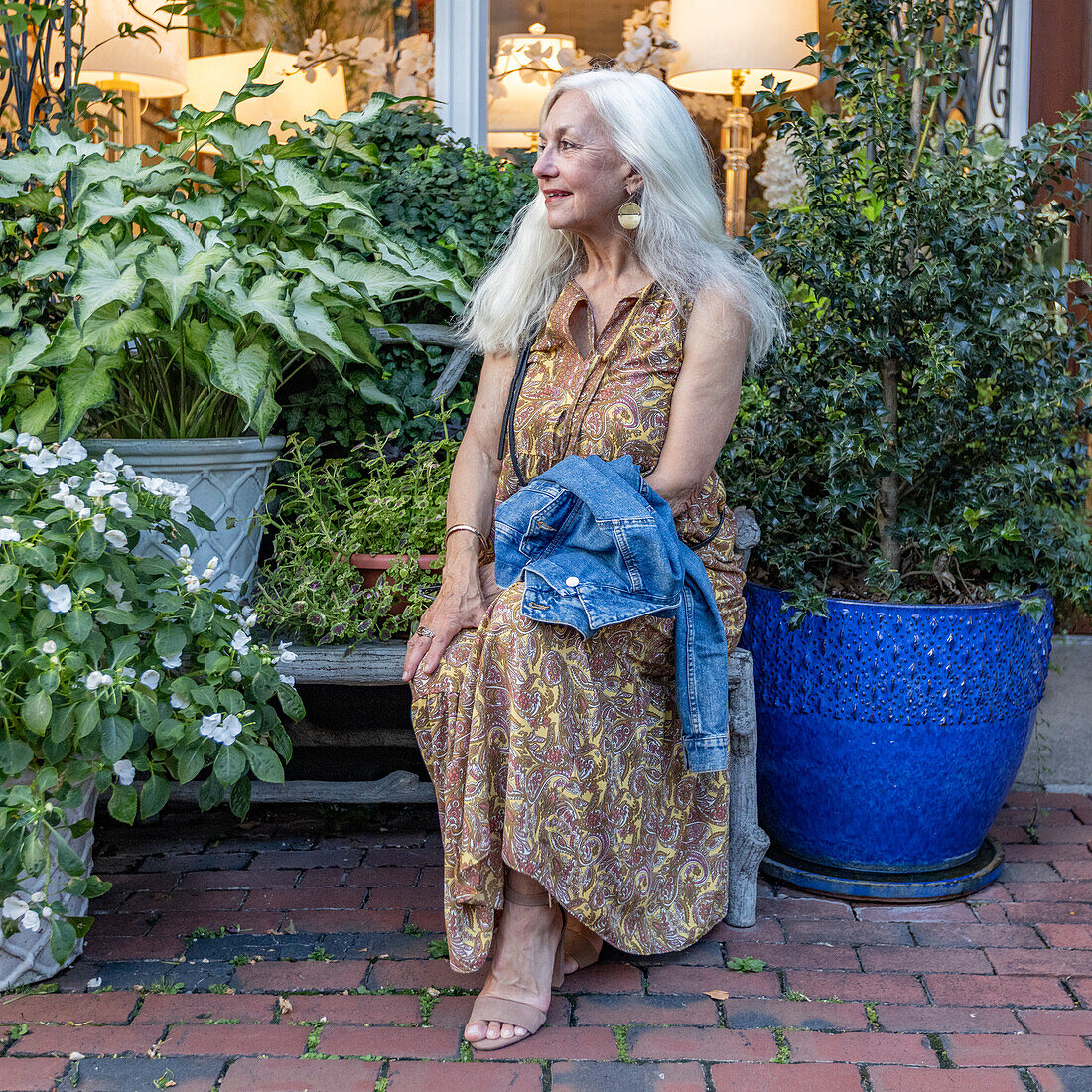 Senior blonde woman sitting on bench in shopping district