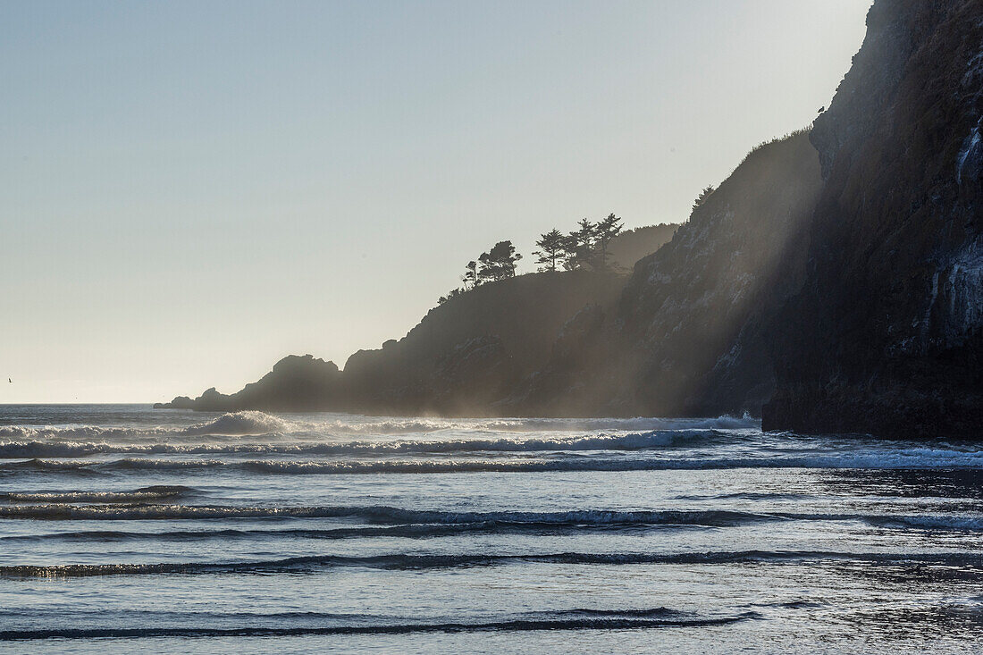 USA, Oregon, Newport, Sonne scheint über felsige Küstenlinie