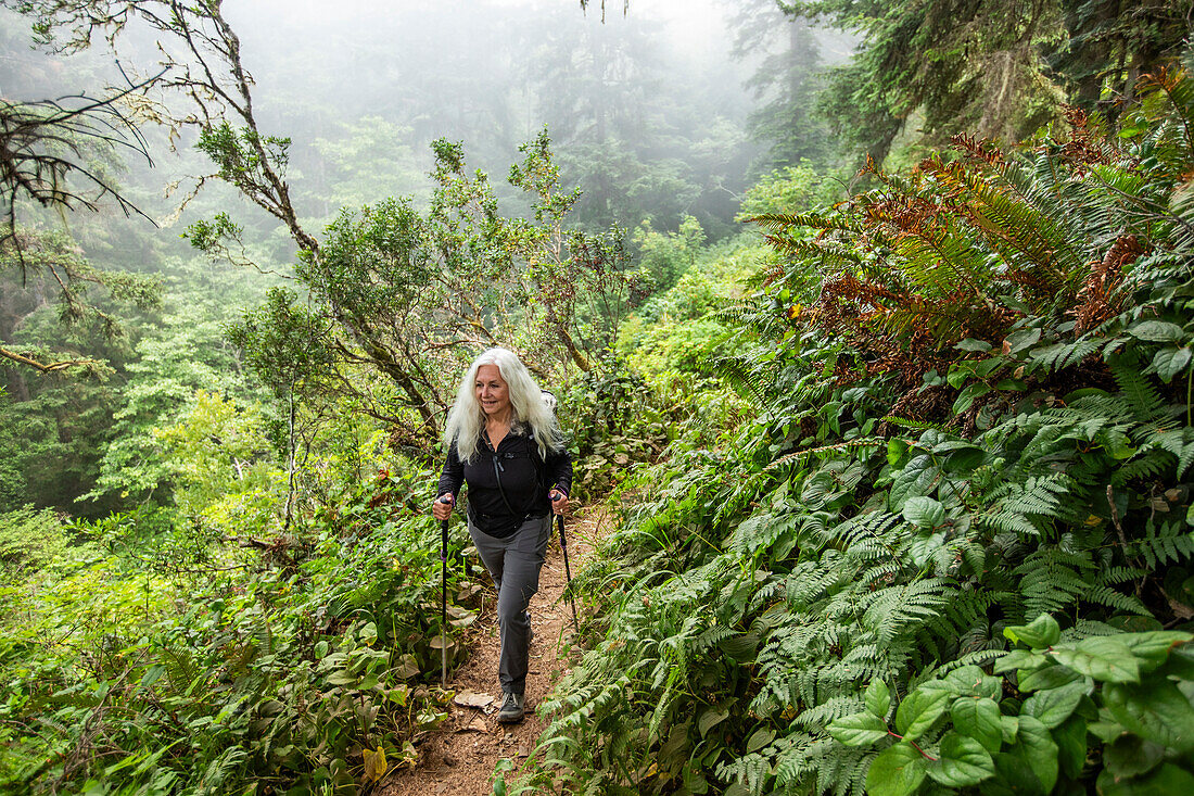 Senior woman hiking on hill with nordic walking poles