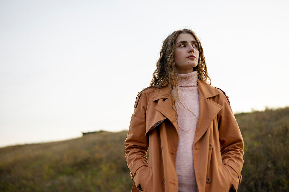 Portrait of serious woman looking away while standing in nature