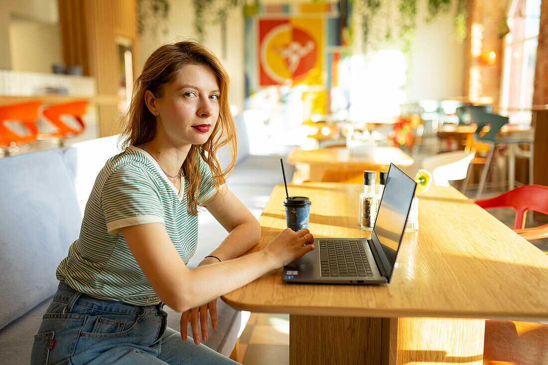 Porträt einer Frau, die in einem Café an einem Laptop arbeitet
