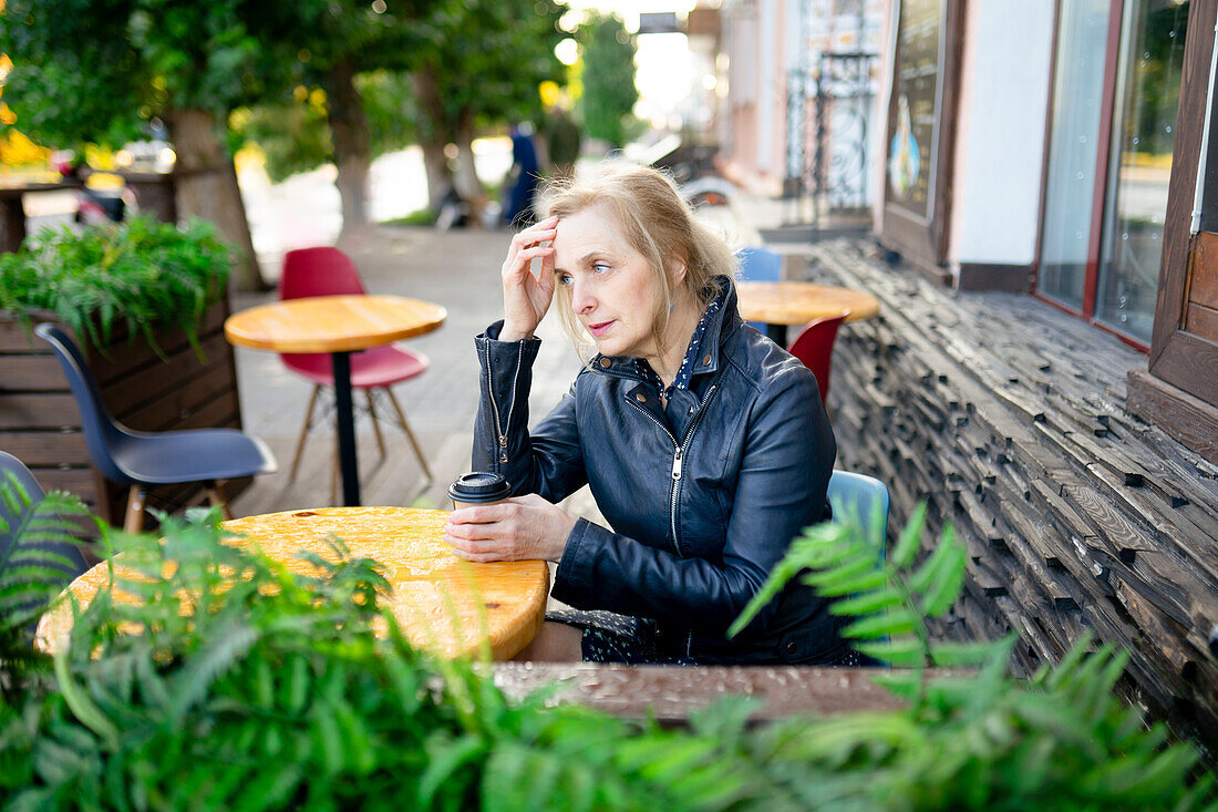 Nachdenkliche Frau trinkt Kaffee in einem Straßencafé