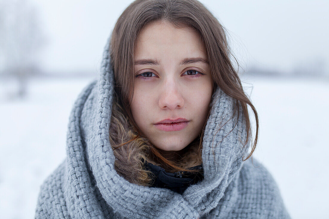 Porträt einer ernsten Frau mit Schal in einer Winterlandschaft