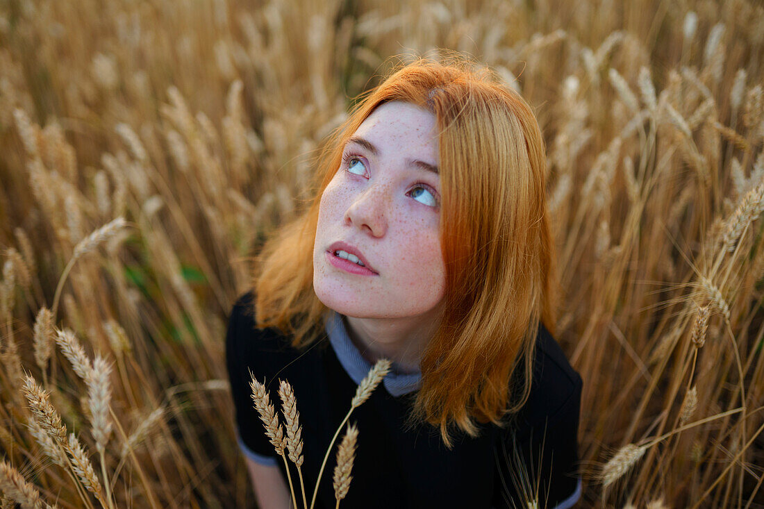 Thoughtful woman looking up while standing in agricultural field